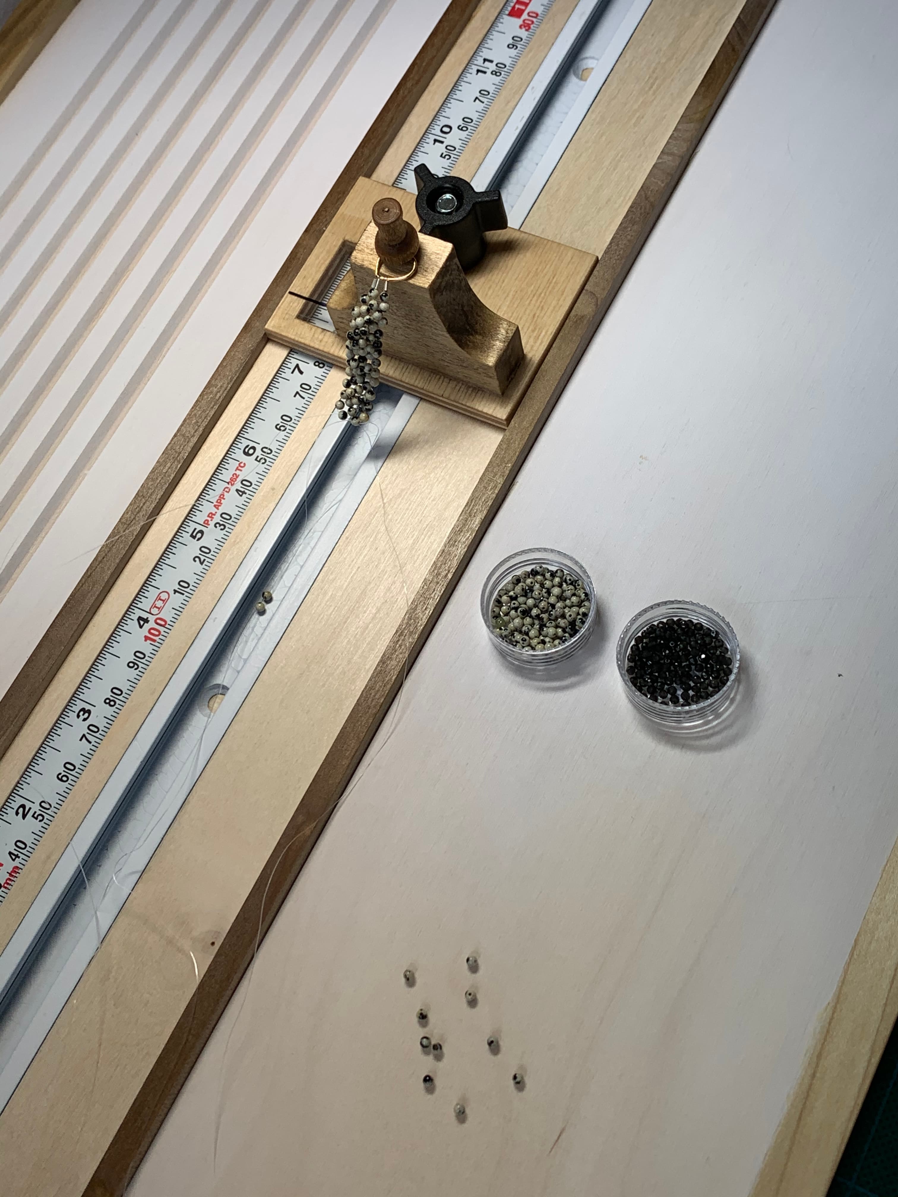Beading measuring board with pearl and gemstone strands in progress